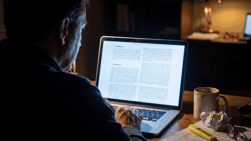 Late-night research into cadmium and brain receptors A researcher reading a scientific study about cadmium and brain insulin receptors late at night